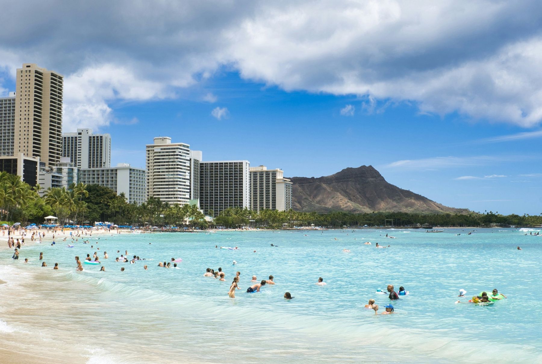 Swimmers in clear water at Waikiki Beach with Diamond Head behind